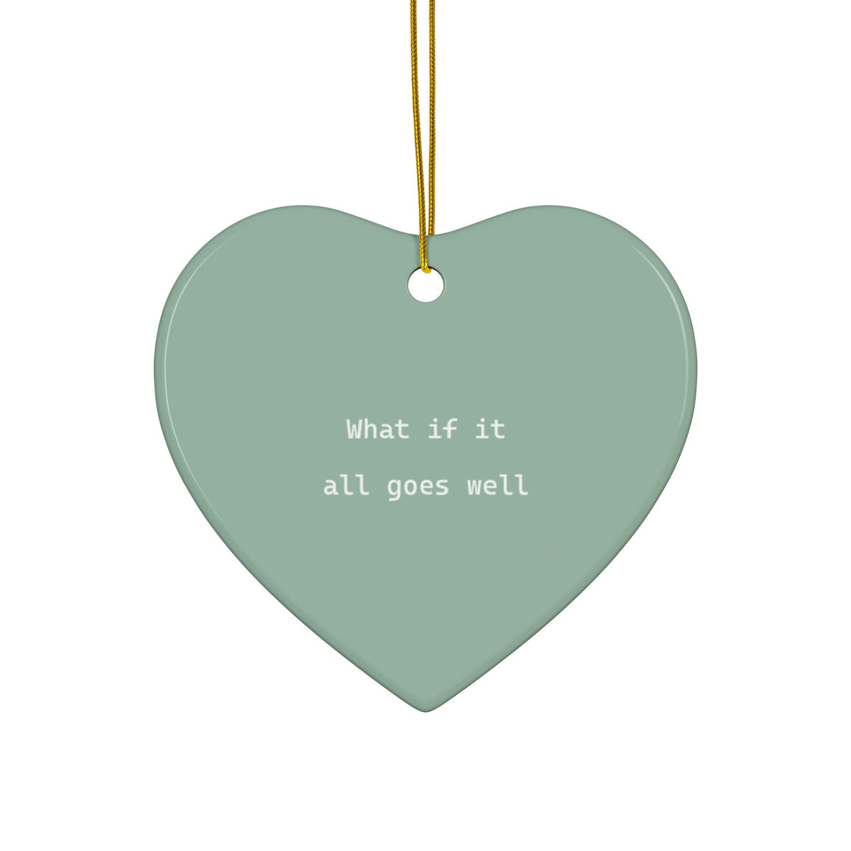 A heart-shaped ceramic ornament in a muted sage green color with the white text 'What if it all goes well' printed in the center. It features a gold hanging string at the top and is shown against a solid white background.