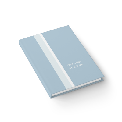 light blue grey hardcover journal notebook with the words, one step at a time