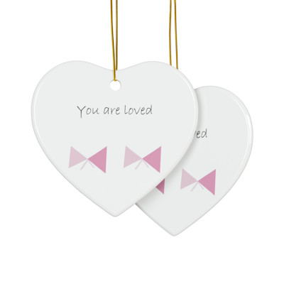 white heart ceramic ornament with two light pink bows and the words, you are loved