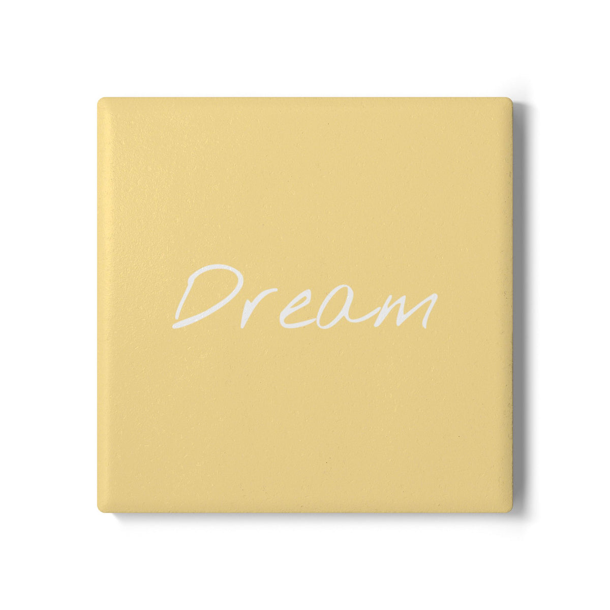 A square yellow coaster with the word 'Dream' written in white cursive script across the center, shown on a clean white background.