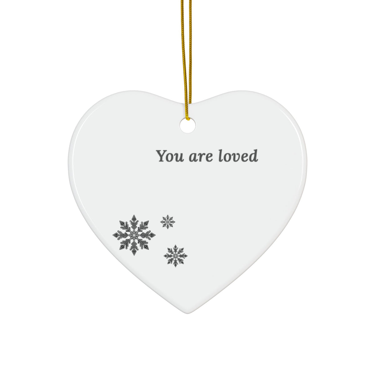 A white heart-shaped ceramic hanging ornament with the printed message 'You are loved' and three gray snowflakes, suspended by a gold string on a white background.