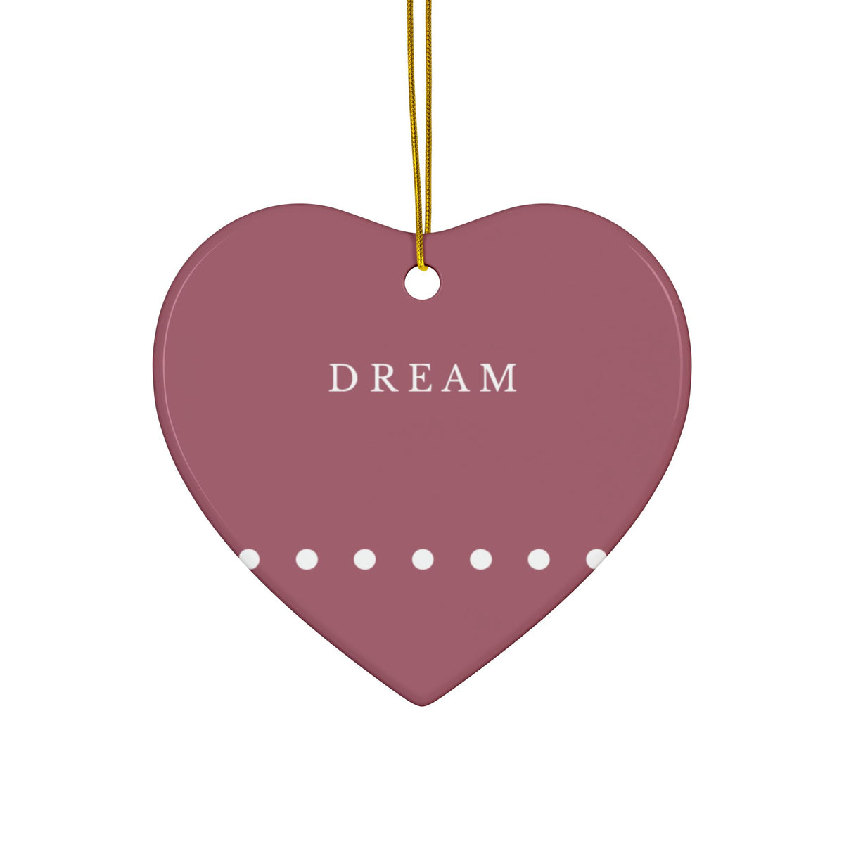 A heart-shaped hanging ornament in dark red with the word 'DREAM' printed in white at the center, a row of white dots along the bottom edge, and a gold hanging string above.