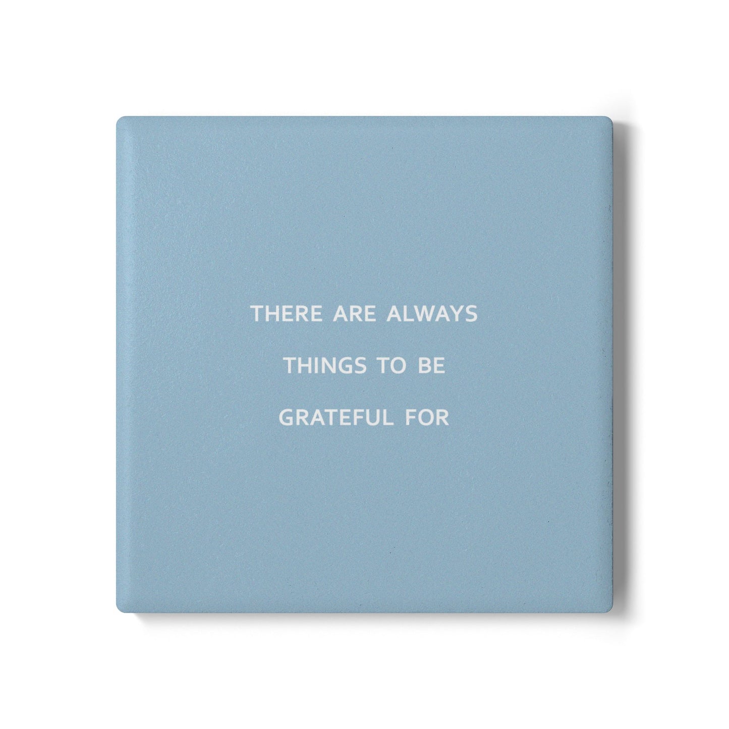 Blue square ceramic coaster with modern style text ‘There are always things to be grateful for’ in white font.