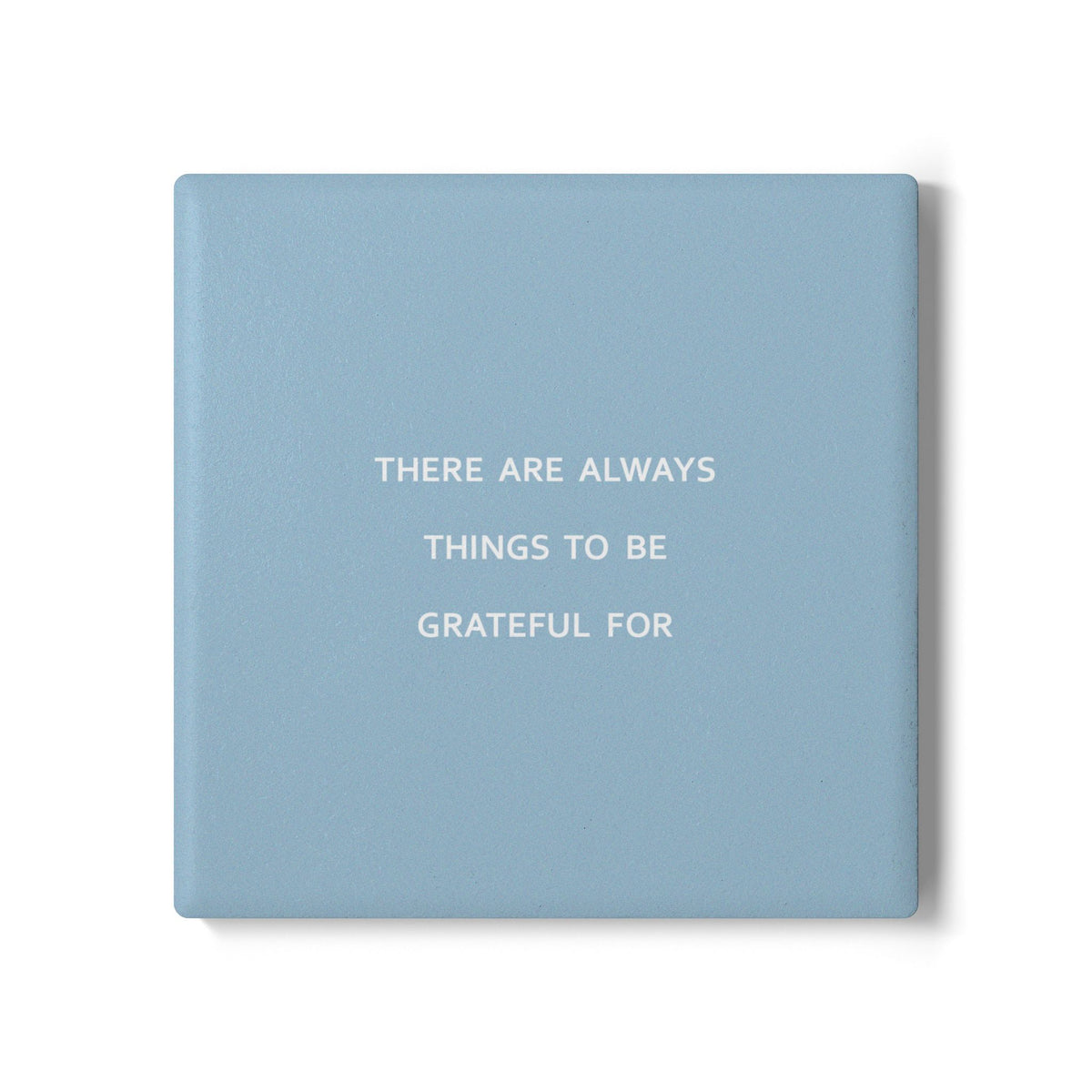 Blue square ceramic coaster with modern style text ‘There are always things to be grateful for’ in white font.