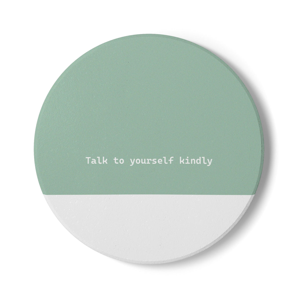 Green and white round ceramic coaster with modern style text ‘Talk to yourself kindly’ in white font. 