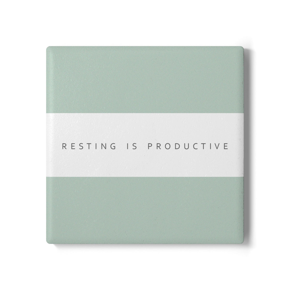 A square coaster with a minimalist design, featuring a sage green top and bottom section divided by a white horizontal band. The band contains the printed text 'RESTING IS PRODUCTIVE' in a clean, sans-serif font.