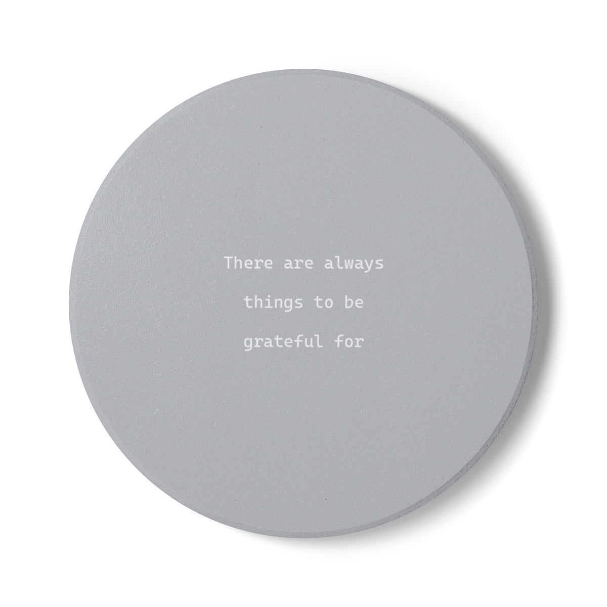 Round grey ceramic coaster with the text 'There are always things to be grateful for' in the middle in small, white font.