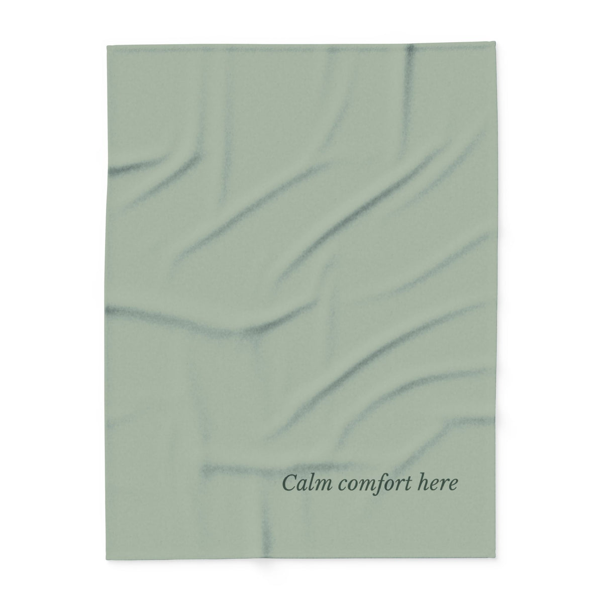 Flat lay of a muted sage green blanket  featuring the text 'Calm comfort here' printed in a dark gray serif font near the bottom.