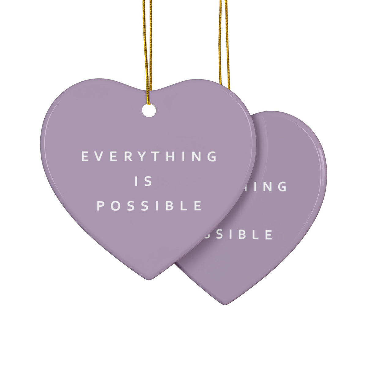 Two lavender heart-shaped hanging ornaments with white text reading 'EVERYTHING IS POSSIBLE' on a white background, suspended by thin gold strings.