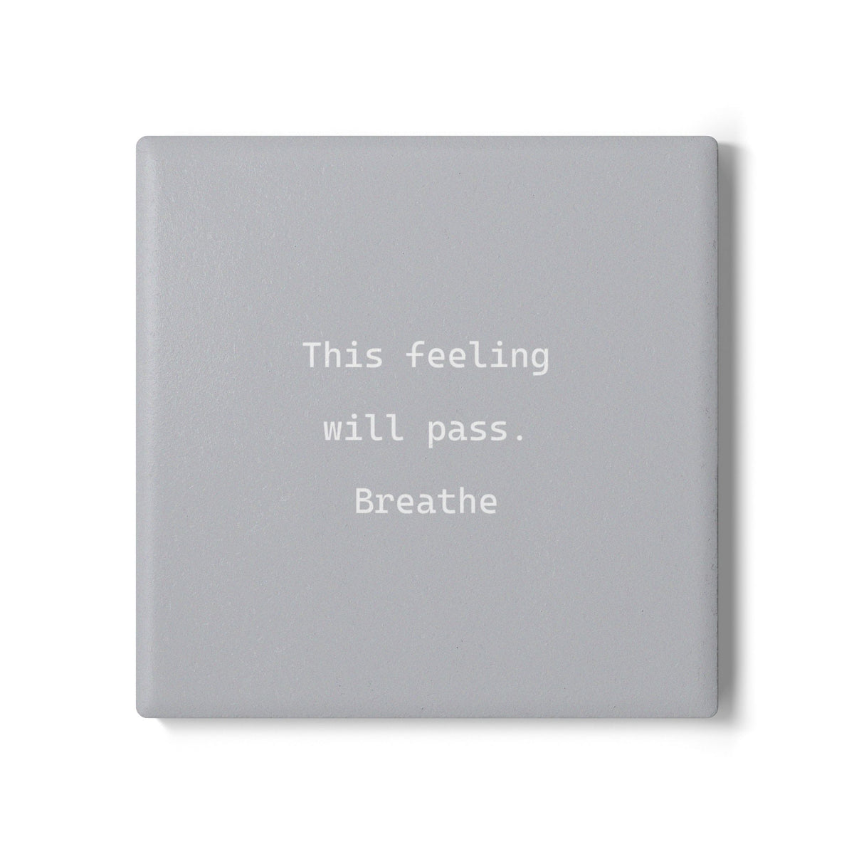 A square gray ceramic coaster and a subtle drop shadow, featuring the text 'This feeling will pass. Breathe' in a white typewriter-style font.