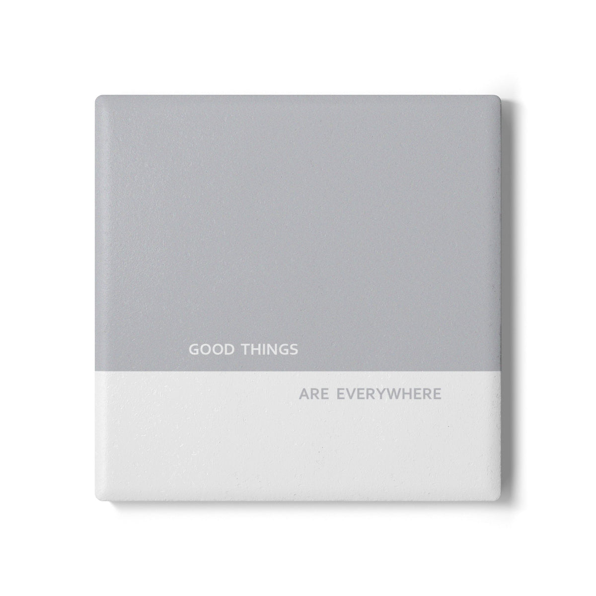 A square gray and white ceramic coaster with the printed text 'GOOD THINGS ARE EVERYWHERE' on the front, shown on a clean white background.