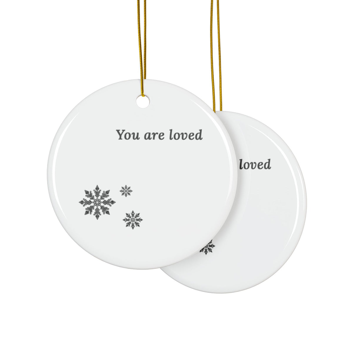 Two round white ceramic Christmas ornaments hanging, overlapping, by gold strings, one showing the front with the text 'You are loved' and gray snowflakes, and the other showing the back with partial text. The same text will be printed on both sides of the ornament.