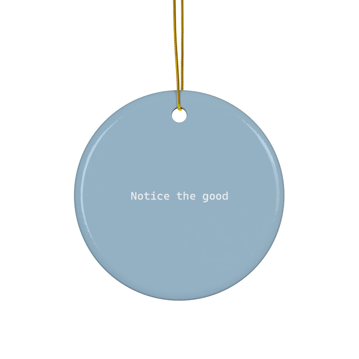 A round light blue ceramic ornament with the phrase 'Notice the good' printed in white text, hanging from a gold string against a plain white background.