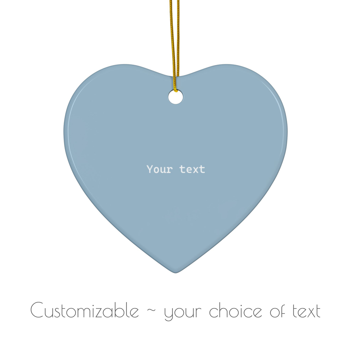 A heart-shaped hanging ornament in a dusty light blue color with a gold hanging string and customizable white text placeholder, shown on a white background with text below indicating it is customizable.