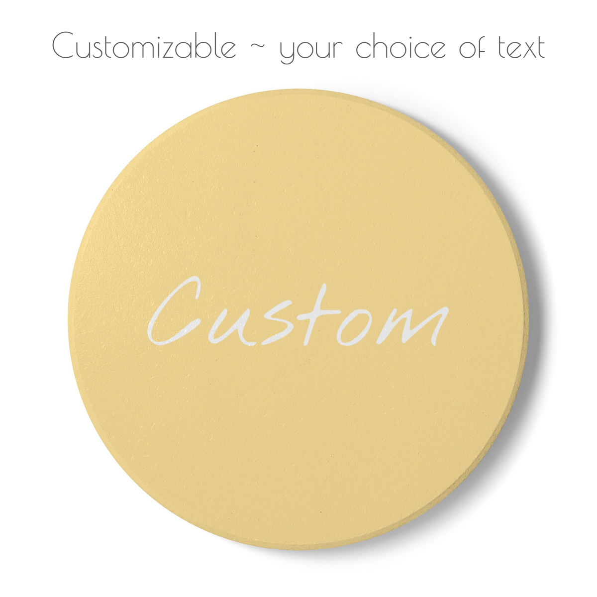 A round pale yellow coaster with the word 'Custom' written across it in white script, shown on a white background with the text 'Customizable ~ your choice of text' above it.
