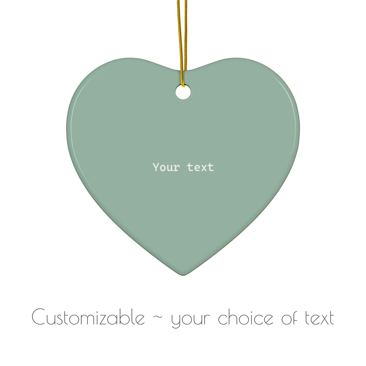 A heart-shaped hanging ornament in a muted sage green color with a gold hanging string and the placeholder text 'Your text' in the center. Below the ornament, the text 'Customizable ~ your choice of text' is displayed on a clean white background.