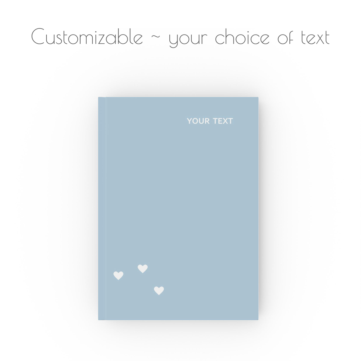 A light blue, hardcover, a5 journal notebook with cluster of three white hearts, and white modern style text that is customizable with your choice of personalized text.