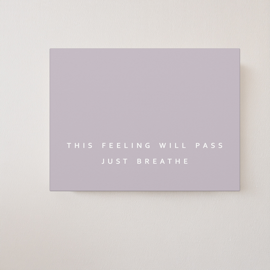 A minimalist wall art canvas print in a taupe brown color with the text 'THIS FEELING WILL PASS JUST BREATHE' in white, shown mounted on a textured off-white wall.