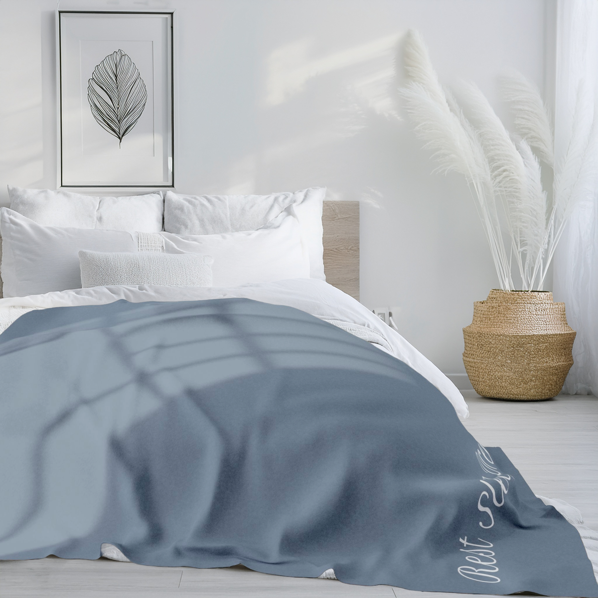 Large version of blue blanket laid over double bed in modern bedroom with large vase, and artwork on the wall above bed. 