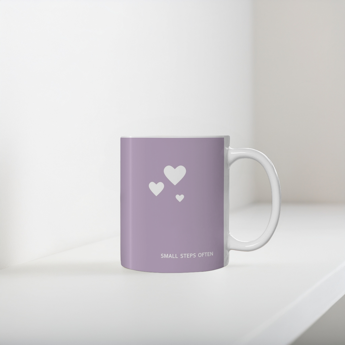 Purple ceramic mug with cluster of three white hearts. Small white font at the bottom ‘Small steps often’. The 11oz mug sits on a white wooden shelf