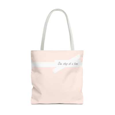 light pink tote bag with the words, one step at a time. white handles